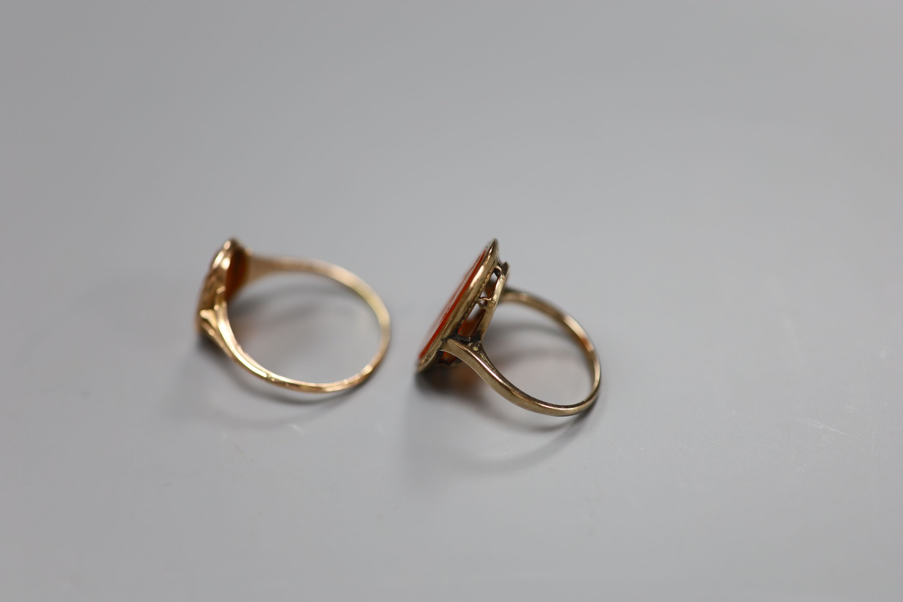 Two 19th century yellow metal and oval carnelian intaglio rings, carved with a bust or figure, one stamped 9ct,